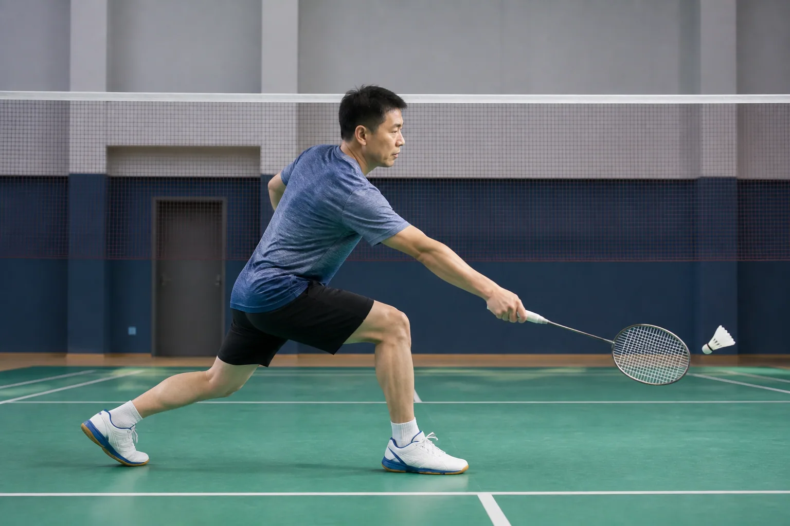 Badminton player reaching a low shuttle with a controlled front-court lunge