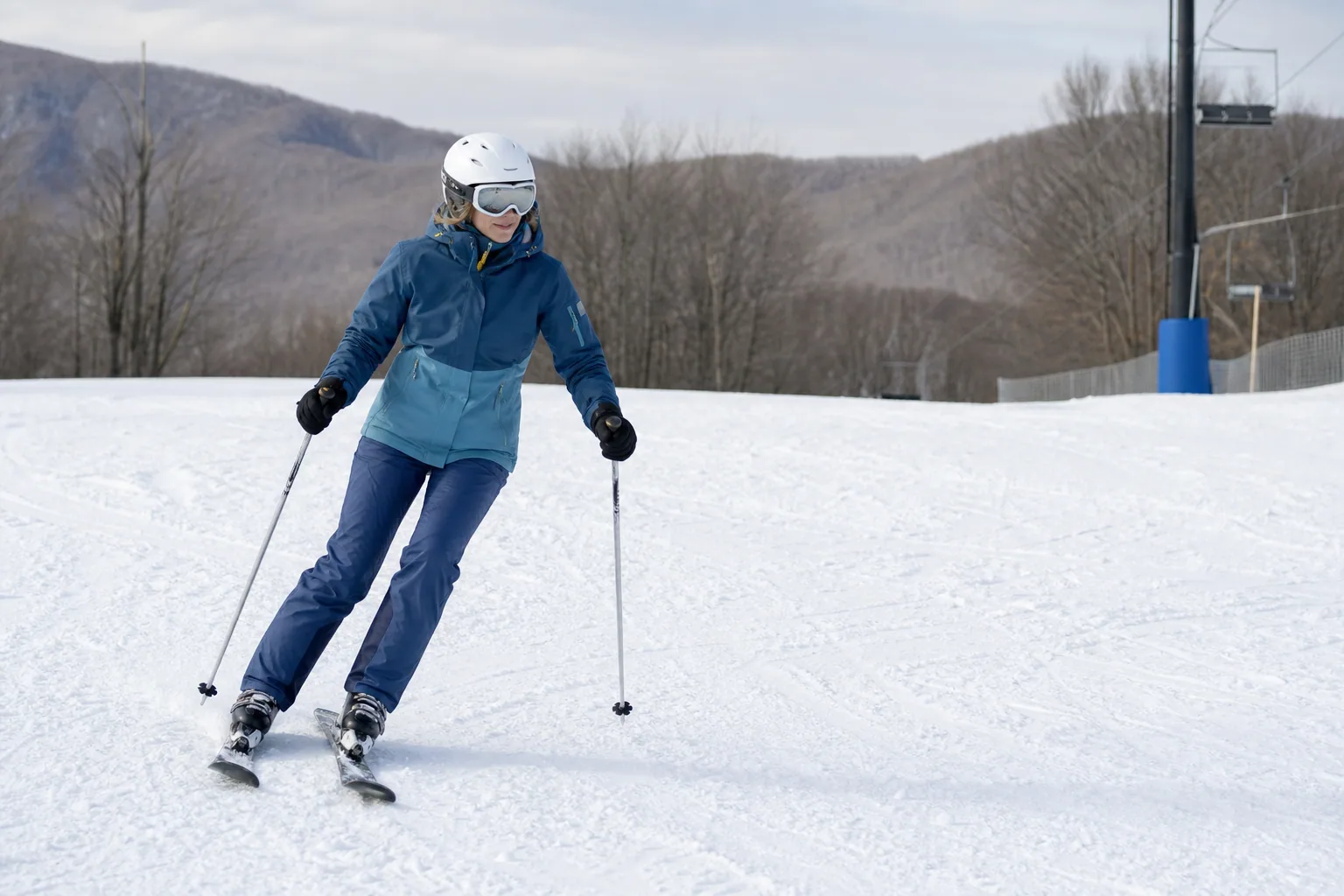 Skier making a controlled turn on a gentle groomed slope with ample space