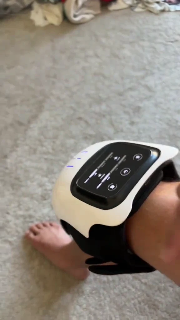 Knee massager secured around a knee, showing the wrap and top control panel